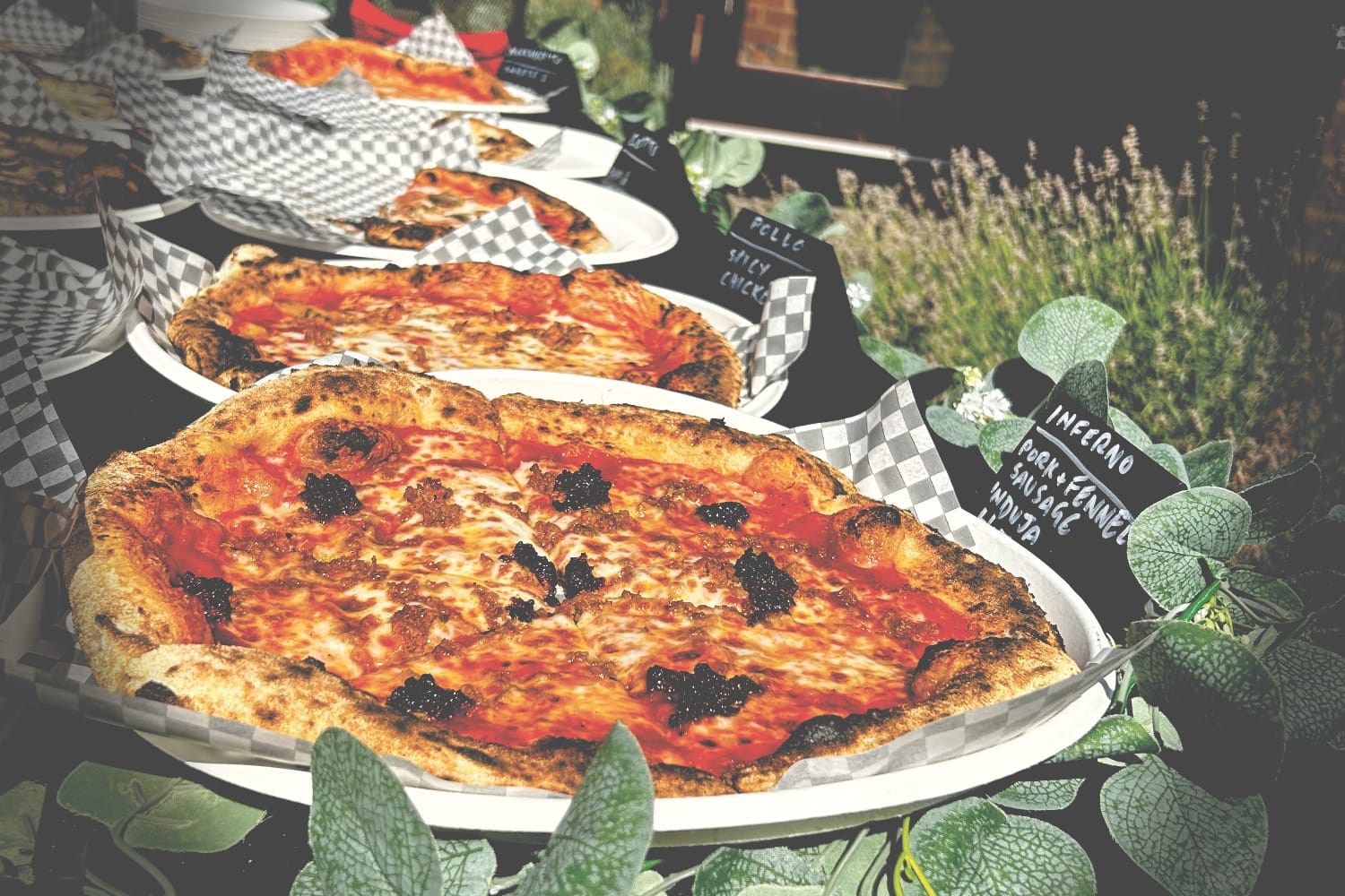 Pizzamici pizzas on a buffet table with plants and flowers